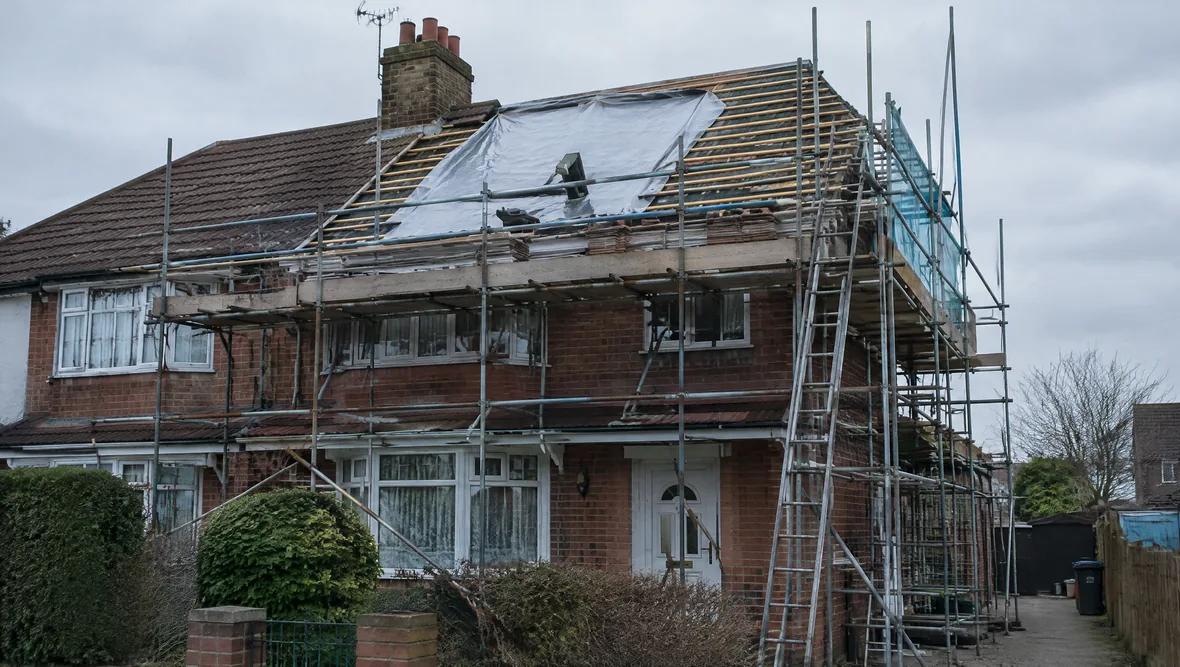 Scaffolding erected against a British house with the roof stripped