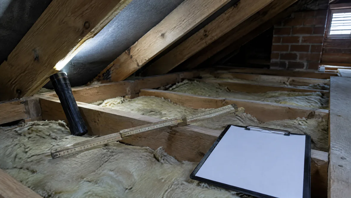 An inspection in progress with a torch and clipboard in a loft